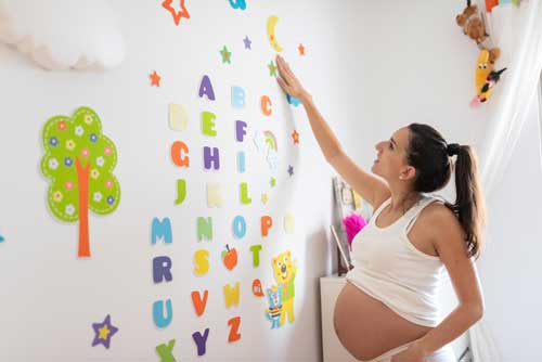 Mujer embarazada frente a letras y dibujos