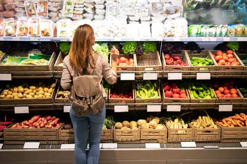 Mujer escogiendo variedad de fruta en frutería