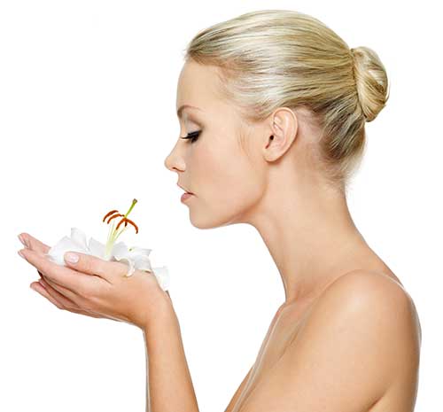 Mujer oliendo flor en la aromaterapia