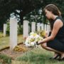 Mujer poniendo flores en cementerio
