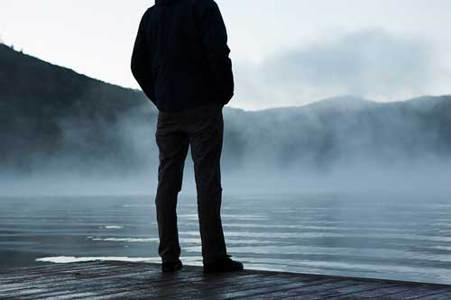 Persona ante un lago con niebla